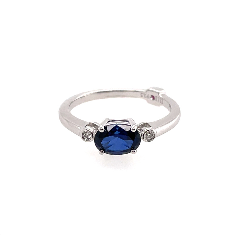 ELLE THREE-STONE RING CONTAINING: 7X5MM OVAL CREATED BLUE SAPPHIRE CENTER; + 2 ROUND BEZEL-SET LAB GROWN DIAMONDS; .03TDW; SILVER